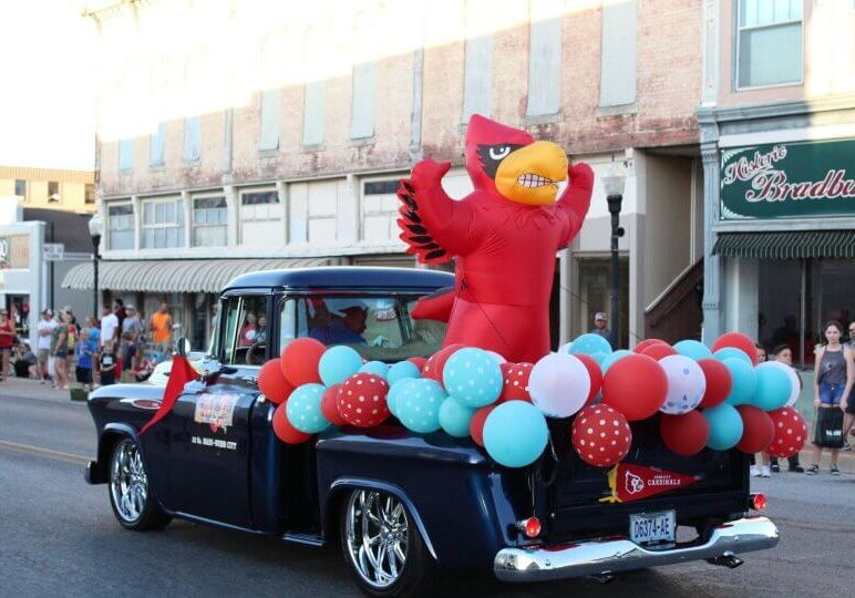 cardinal mascot in antique truck in parade